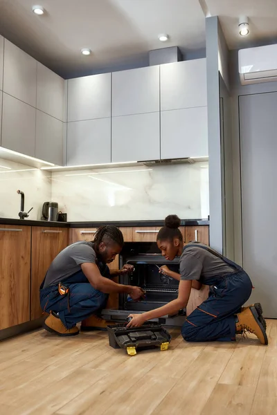 Técnico experimentado enseñando a joven aprendiz a reparar el horno — Foto de Stock