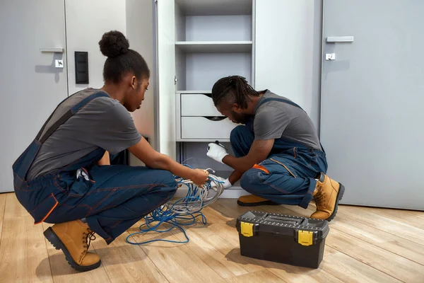 Dos profesionales desenredando el cable de Internet en casa — Foto de Stock