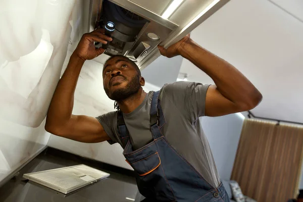 Obrero guapo comprobando filtros de escape de cocina con linterna — Foto de Stock