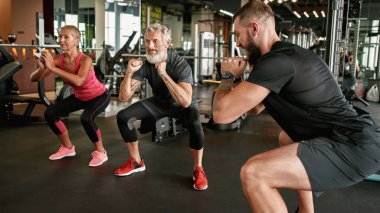 Yetişkin bir çiftin antrenörle birlikte çömelmesi çok motive edici.
