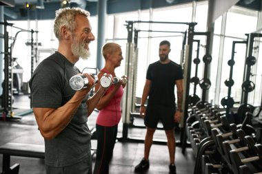 Yaşlı adam halterlerle spor yapmayı seviyor.