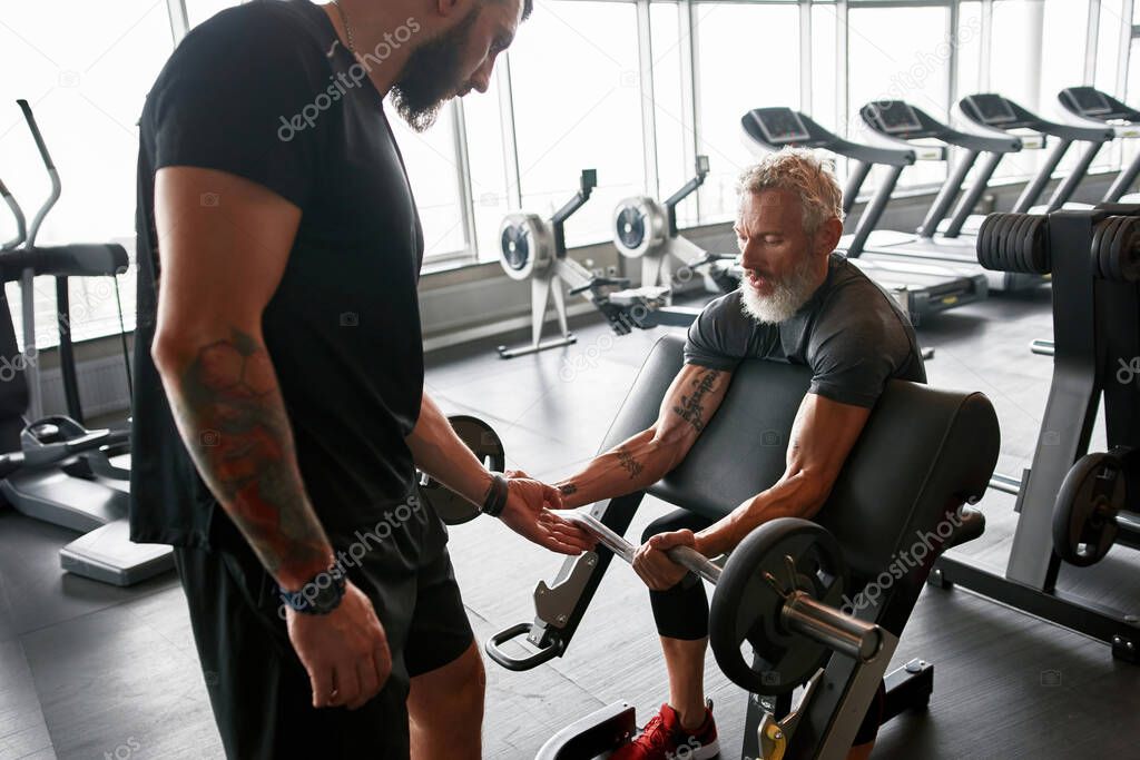 Confident personal coach standing close to senior man