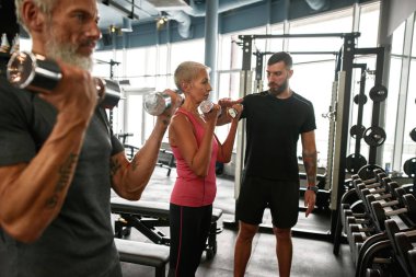 Son sınıf öğrencisi kararlı bir kadın ve spor salonunda dambılı bir erkek.