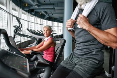 Bisiklet makinesinde egzersiz yapan yaşlı bir kadın.