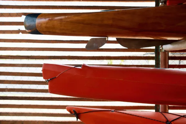 Different kayaks on iron net background in storage — Stock Photo, Image
