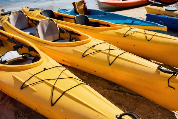 Set of kayaks in row on beach near water — Stock Photo, Image