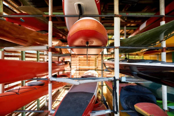 Set of water colorful kayaks on shelves in storage — Stock Photo, Image
