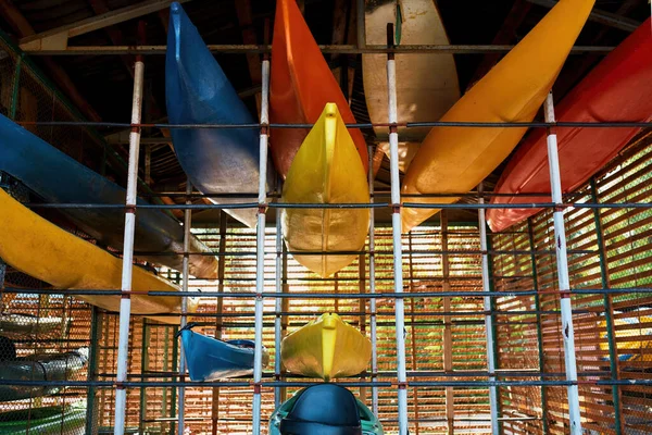 Set of colorful kayaks on shelves in storage — Stock Photo, Image