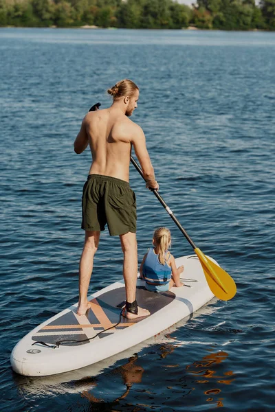 男人骑他的小女孩在皮划艇上划桨 — 图库照片
