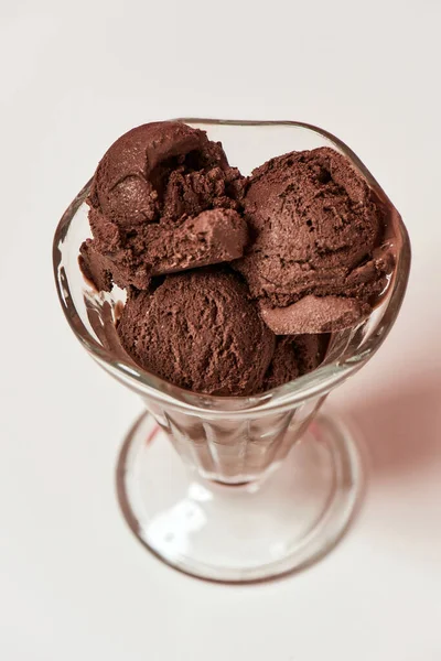 Vista superior de las cucharadas de sabroso helado de chocolate en un plato de helado de vidrio aislado sobre fondo claro —  Fotos de Stock