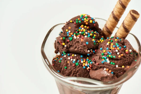 Крупный план вкусного шоколадного мороженого, посыпанного сладким зерном и вафельными палочками для десерта, изолированного на светлом фоне — стоковое фото