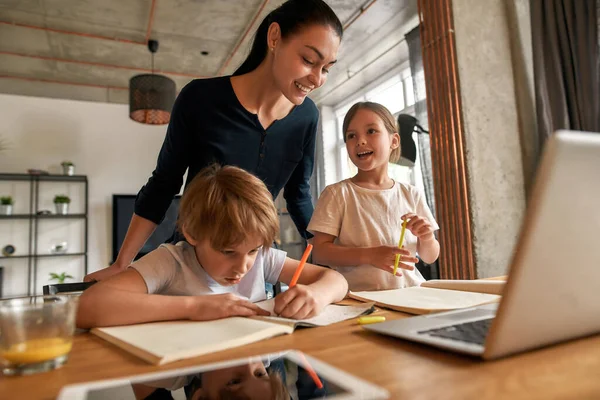 Sorrindo mãe e filhos adolescentes fazer lição de casa no computador — Fotografia de Stock