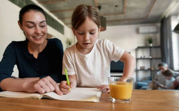 Маленькая семерка девочка делает домашнее задание с мамой — стоковое фото