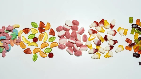 Pile de bonbons gommeux multicolores savoureux dans différentes formes isolées sur fond blanc — Photo