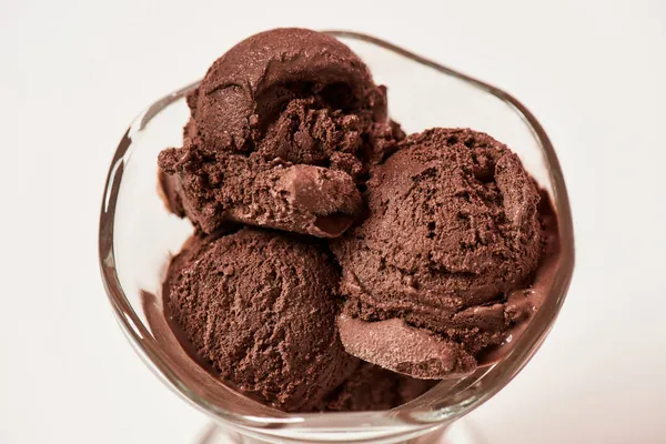 Close up de colheres de sorvete de chocolate saboroso em um prato de sundae de vidro isolado sobre fundo claro — Fotografia de Stock