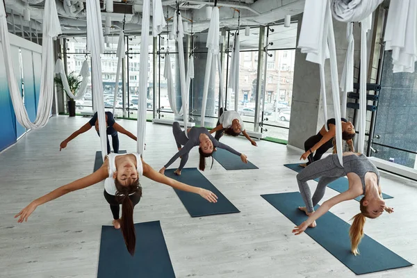 Las mujeres deportivas multiétnicas tienen clase de yoga con mosca juntas —  Fotos de Stock