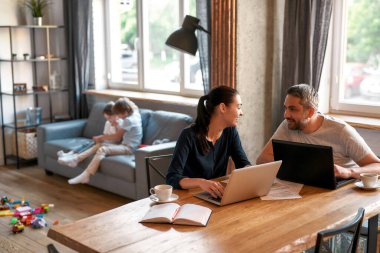 Gülümseyen ebeveynler evdeki bilgisayarlarda çalışır.