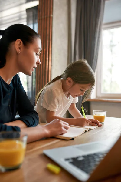 Colpo verticale di mamma imparare a casa con la piccola figlia — Foto Stock