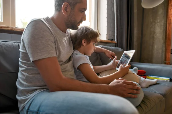 Pai caucasiano relaxar em casa com o filho usando tablet — Fotografia de Stock