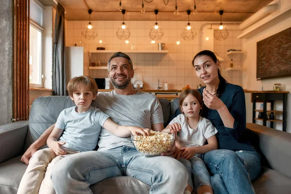 Счастливые родители с детьми смотрят телевизор есть попкорн — стоковое фото