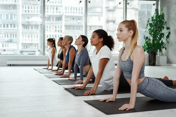 Diversas mujeres practican yoga meditando en el entrenamiento en grupo —  Fotos de Stock