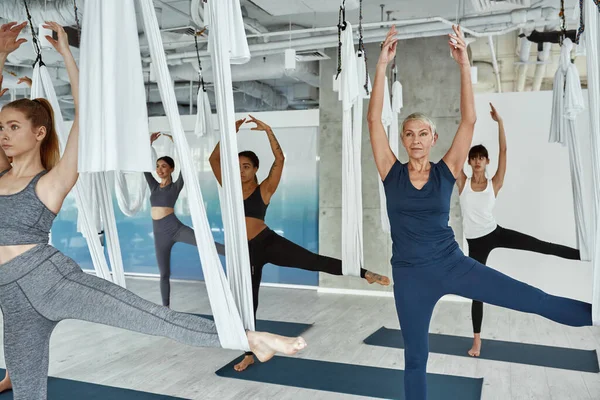 Diverse female group have fly yoga class together