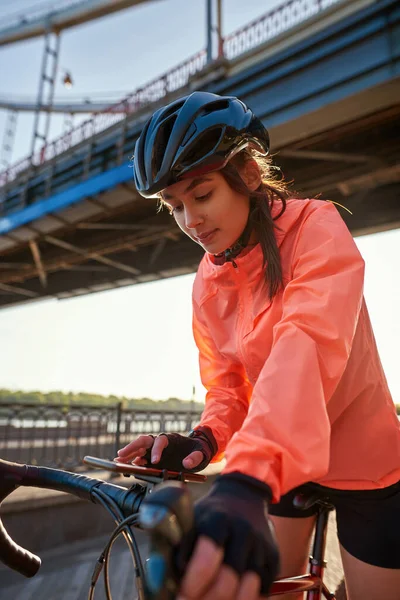 Sporty female on bicycle use internet cellphone app