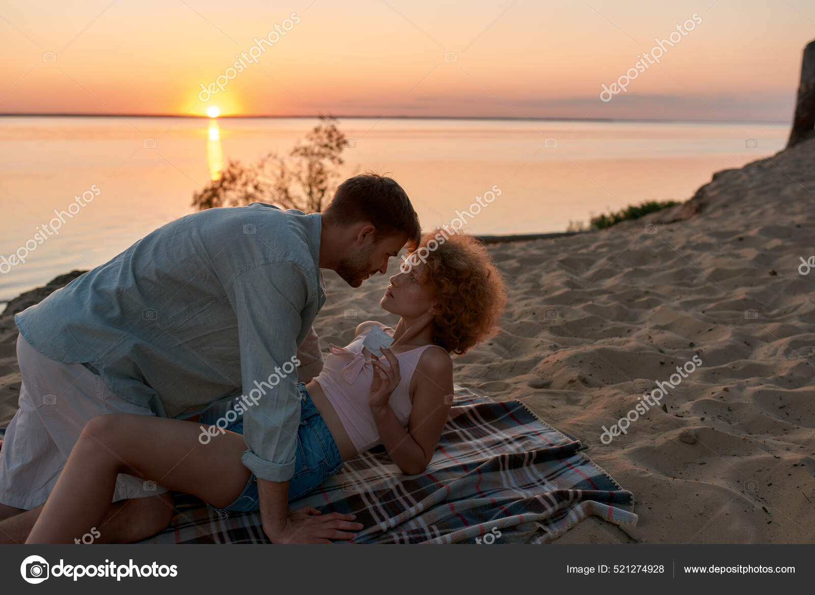 Beautiful young couple lying on the beach at sunset, ready for making love