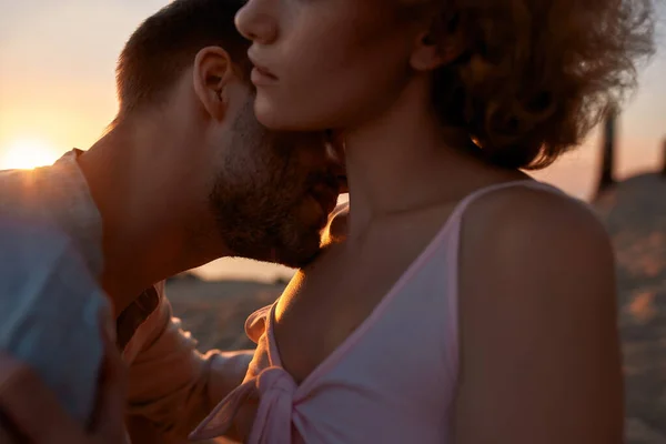 Plan recadré d'un jeune homme embrassant une femme sur sa clavicule. Couple profitant de l'autre sur la plage au coucher du soleil — Photo