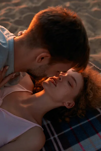 Young couple in love kissing while spending time together on the beach at sunset — Stock Photo, Image