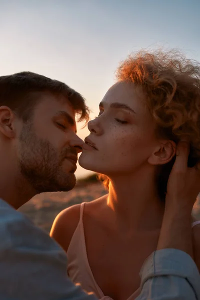 Beaux jeunes amoureux, couple à la recherche passionné, s'embrassant sur la plage au coucher du soleil — Photo