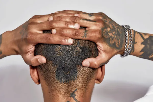 Közelkép tetovált fej, nyak és karok fiatal sötét bőrű férfi pózol elszigetelt fehér háttér — Stock Fotó