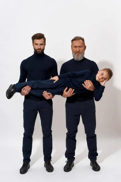 Porträtt av tre generationer av män poserar i studio — Stockfoto