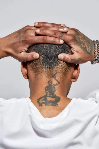 Vissza kilátás borotvált tetovált fej és nyak fiatal sötét bőrű férfi pózol elszigetelt fehér háttér — Stock Fotó