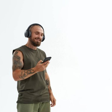 Genç adam kulaklıkla akıllı telefondan müzik dinliyor.