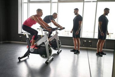 Jimnastik bisikletine binen kararlı yaşlı kadın ve erkek