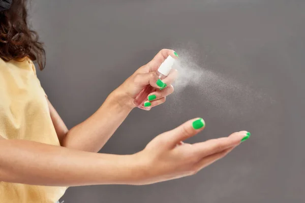 Fechar as mãos femininas. Mulher aplicando spray de álcool desinfetante em mãos isoladas sobre fundo cinza — Fotografia de Stock