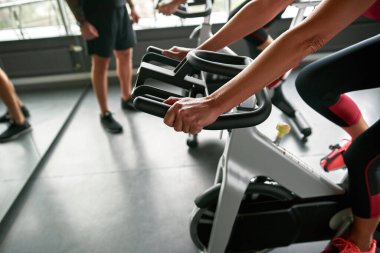 Egzersiz bisikletinin gidonundaki kadın elleri