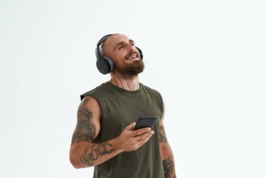 Neşeli adam akıllı telefondan kulaklıkla müzik dinler.