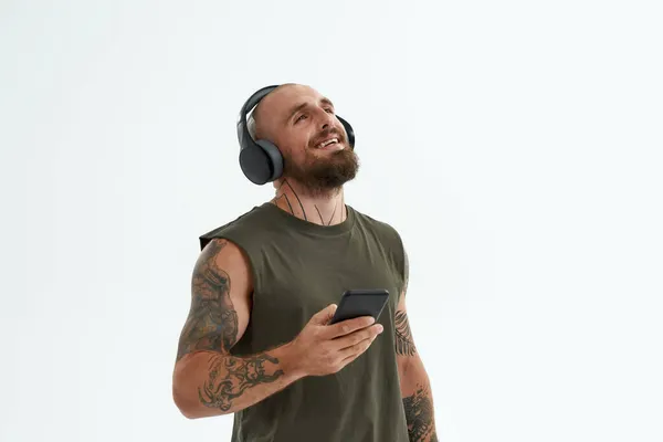 Homem alegre ouvir música em fones de ouvido no smartphone — Fotografia de Stock