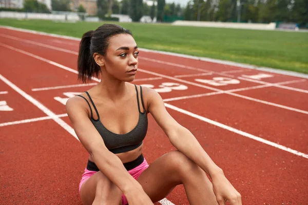 Ung sport kvinna sitter på stadion löpband — Stockfoto