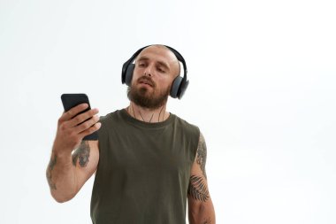 Kulaklıklı bir adam akıllı telefondan bir şey izliyor.