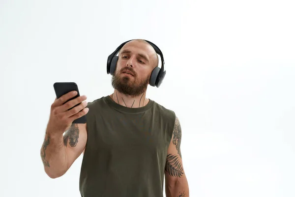 Homem em fones de ouvido assistindo algo no smartphone — Fotografia de Stock