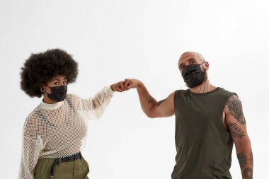 Beyaz adam ve siyah kız yumruk tokuşturuyor.