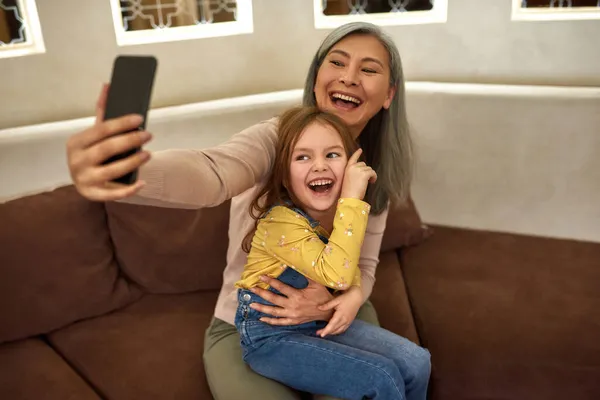 Criança e mulher sênior fazendo chamada on-line de casa — Fotografia de Stock
