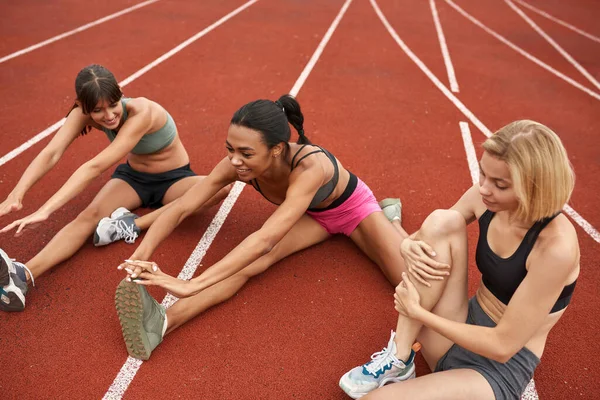 Grupo de chicas estirándose en la cinta de correr del estadio — Foto de Stock