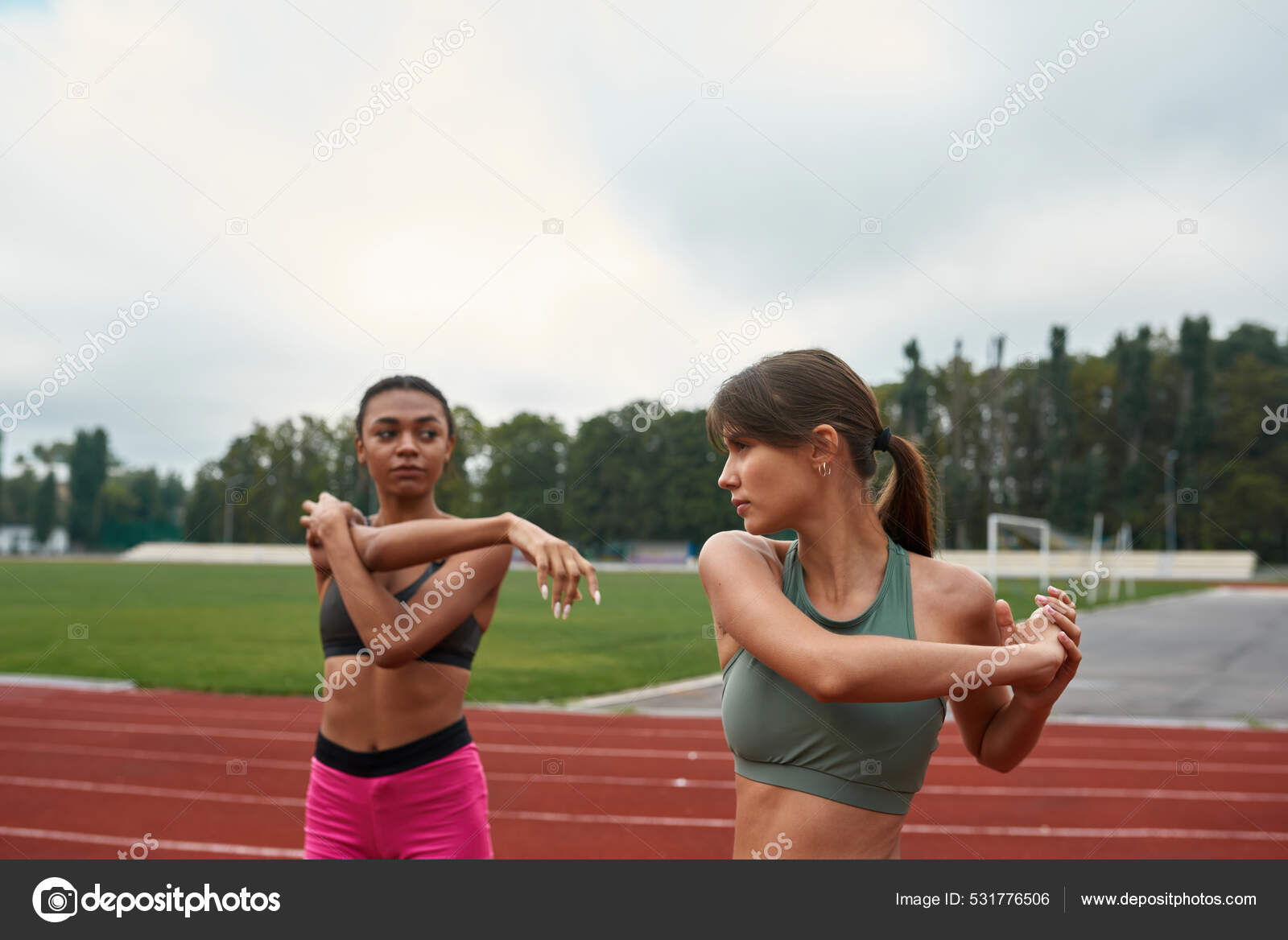 Women stretching before run training on stadium Stock Photo by