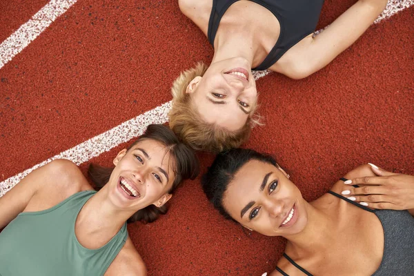 Ovanifrån av glada idrottskvinnor som ligger på löpband — Stockfoto