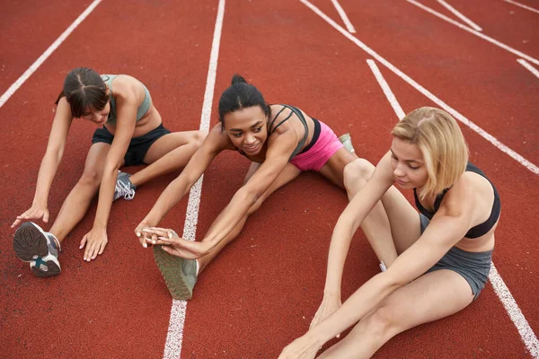 Grupo de mujeres estirándose en la cinta de correr del estadio — Foto de Stock