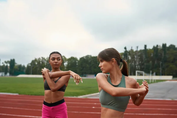 Kvinnor stretching innan springa träning på stadion — Stockfoto